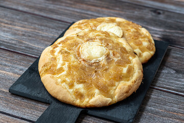 Salty pastries with caramelized onion and gratin goat cheese, on a wooden backgroun