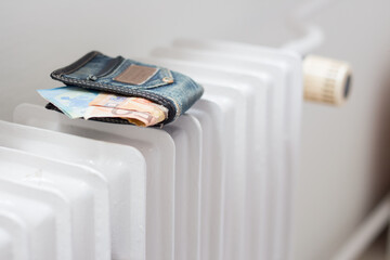 Wallet with money on the heating radiator in the apartment. Increasing the cost of energy due to...