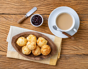Typical brazilian cheese bun in a plate with coffee latte and jam over wooden table