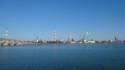 Naklejka premium 青い空と青い海の対岸に広がる工場群