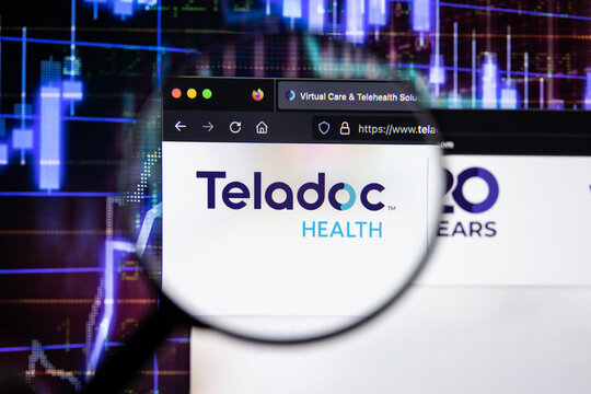 Teladoc Health company logo on a website with blurry stock market developments in the background, seen on a computer screen through a magnifying glass