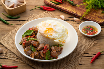 Stir-fried Chicken Giblets(livers, heart and gizzards) with Chillies and basil in white plate with cooked rice and put on top of a fried egg