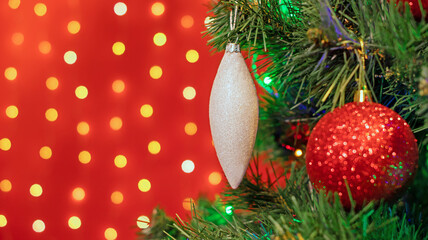 Christmas decorations hung on a Christmas tree against a red background.
Ozdoby choinkowe zawieszone na choince na czerwonym tle.