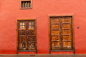Fachada de casa en color caldero con puertas de madera antiguas.