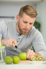 Fototapeta premium young man cutting fruit in the kitchen