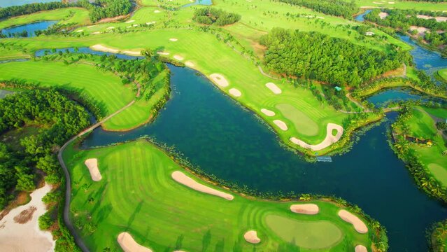 Aerial view over beautiful golf field landscape during sunset. hobby and sports concepts. Tropical golf course in Southeast asia. summer day. green nature background. drone footage. cinematic shot 4K
