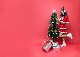 Young asia woman in red santy costume decorate the Christmas tree. New Year celebration. Christmas eve.
