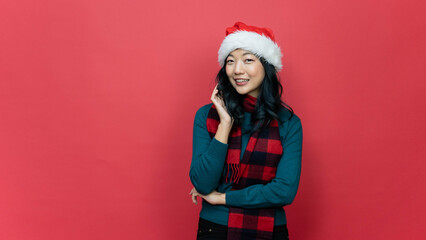 Smiling beautiful asia woman ware santa hat on red background. Concept of the New Year and Christmas Day.