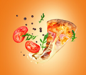 Hot slice of pizza with melted cheese and ingredients in the air on orange background