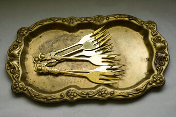 Antique golden trays with set of antique forks on a rustic table - Top of view banner. Vintage...