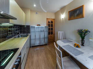 Modern simple interior of kitchen. White table and chairs. Sink and oven. Wooden door.