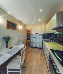 Modern simple interior of kitchen. White table and chairs. Sink and oven. Wooden door.