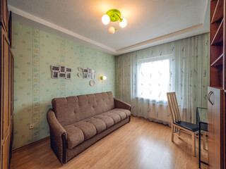 Modern interior of living room in apartment. Empty wooden shelves. Chair and glass table. Cozy sofa.