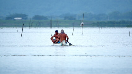 Fototapeta na wymiar Two men paddling a boat in the La Segua wetlands near Chone, Ecuador