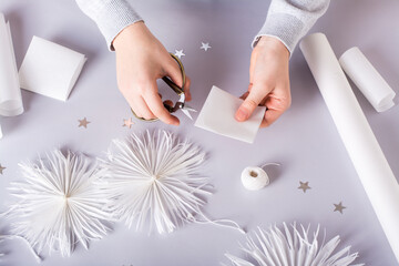 Children's hands hold paper for cutting out a Christmas snowflake. Handmade decor