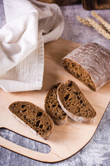 Italian rye ciabatta bread sliced on a wooden board on the table. Vertical view