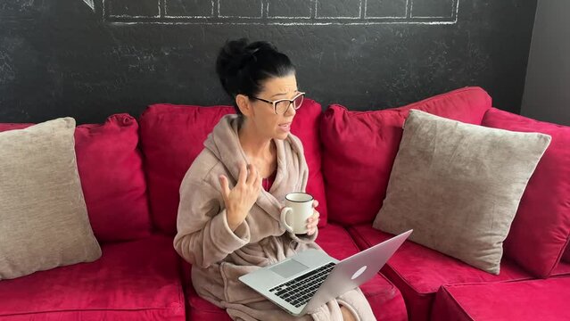 sad woman in online therapy session holding a coffee cup, talking and listening