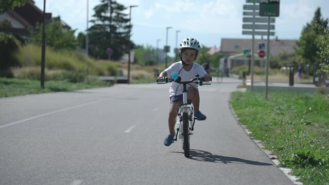 One active cyclist child wearing helmet rides bike. Actice little kid exercising outdoors in green city path road