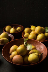 Fototapeta na wymiar Delicious juicy pears in clay plates on dark background in rustic style.