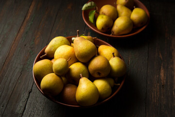 Delicious juicy homemade pears in clay plates on dark background