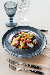 A waiter pours sauce over a fresh salad of vegetables and tuna in close-up. Healthy food. Exquisite delicacies of haute cuisine close-up.