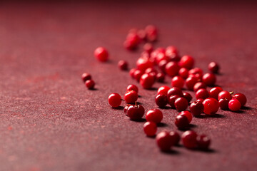 Delicious lingonberry berry scattered on a burgundy background