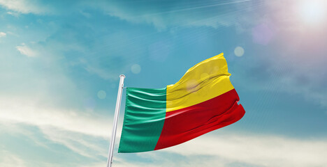 waving flag of Benin in blue sky. the symbol of the state on wavy cotton fabric.