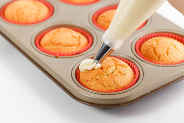 Decorating cupcakes with white cream using pastry bag with white cream. Making homemade cupcakes. Process. Decorating Bag with pastry tube.