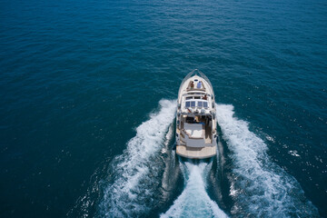 Big white yacht with people moving on blue water top view. Yacht in the sea aerial view. Summer travel on a yacht aerial view.