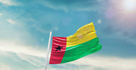 waving flag of Guinea-Bissau in blue sky. the symbol of the state on wavy cotton fabric.
