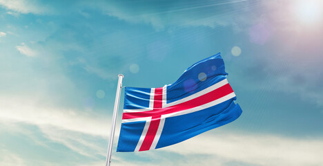 waving flag of Iceland in blue sky. the symbol of the state on wavy cotton fabric.