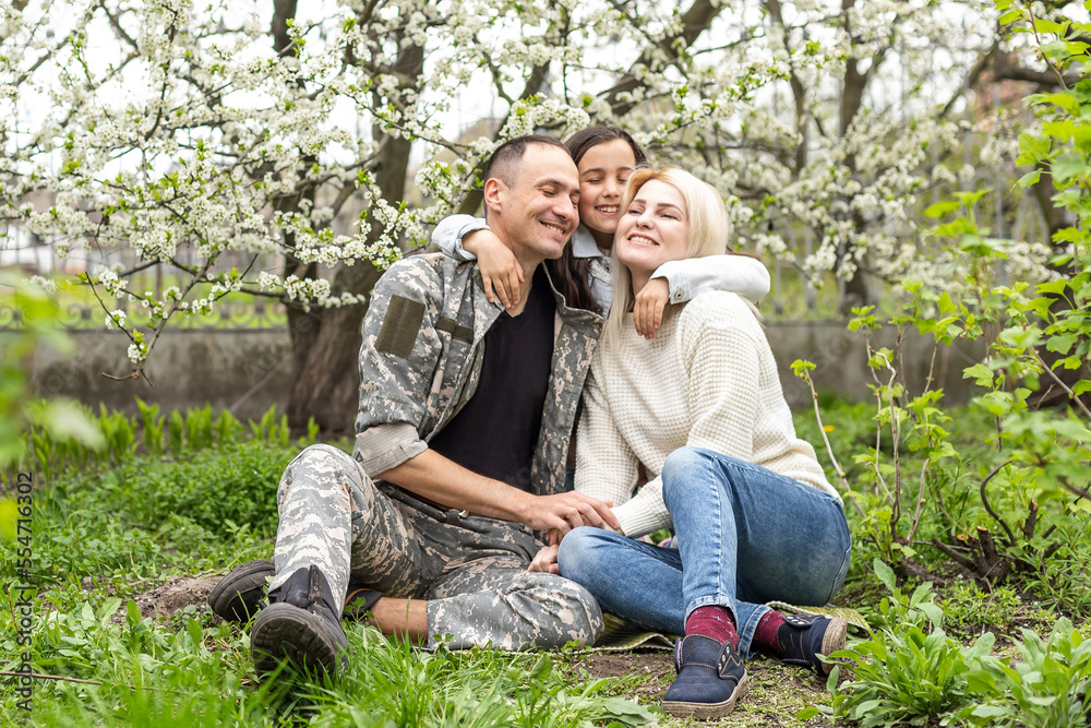 Wall mural soldier is meeting his family outdoors. happy reunion of father and kids on the grass