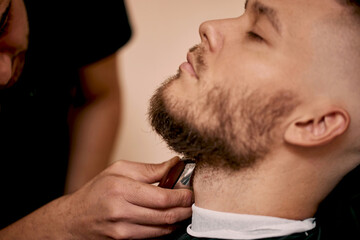 Barber shaving caucasian man in barber shop
