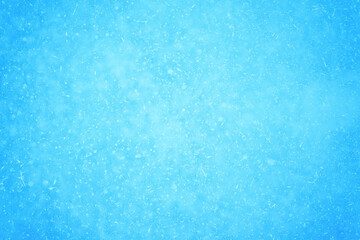Blue ice interspersed with snowflakes and white frost in a natural light haze. Background
