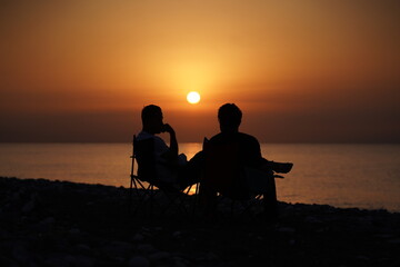 Fototapeta na wymiar two boys sitting by the beach at sunset