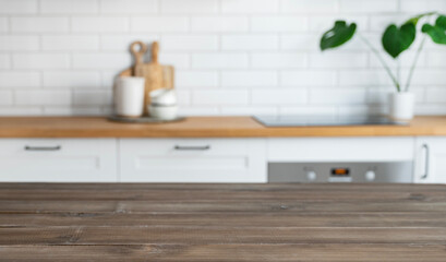 Obraz na płótnie Canvas Dark wooden countertop with free space for mounting a product or layout against the background of a blurred white kitchen with plant.