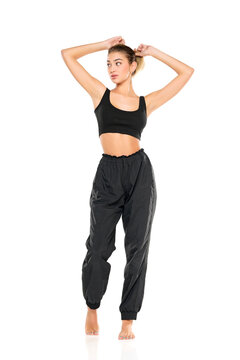 a young barefeet woman in black sweatpants and a tank top on a white background