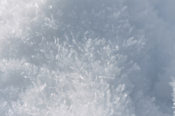 Winter background with sunlight on detailed snow crystals and snowflakes.
