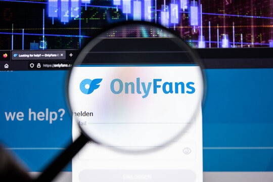 Onlyfans company logo on a website with blurry stock market developments in the background, seen on a computer screen through a magnifying glass