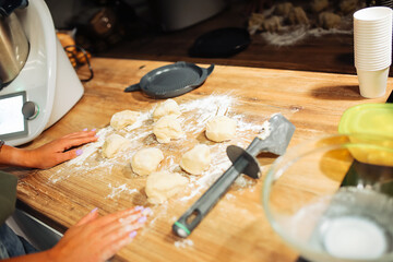 Unrecognizable cropped woman floury hands cooking, baking biscuits or pies on wooden board near mixer in the kitchen. 