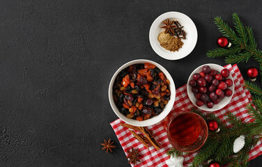 Ingredients for Christmas fruit cake on dark background ,nuts and dried fruits soaking up added brandy in the ceramic bowl. Top view. copy space