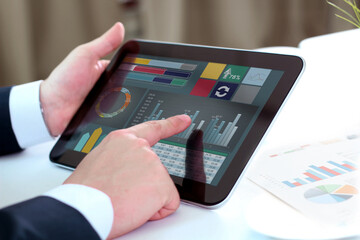 Businessman working and analyzing financial figures on   a tablet.