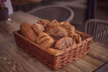 Composition with a variety of pastries in a basket on a wooden table.