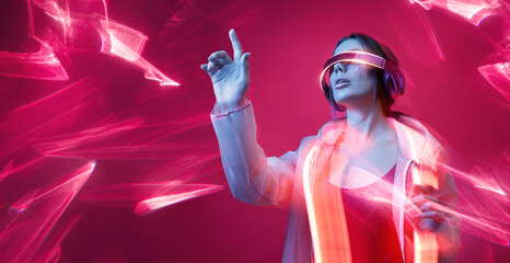 Woman in futuristic costume. Girl in glasses of virtual reality while touching air. Augmented...