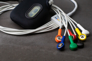 Holter, a medical device for a heart rate measurement with all the colorful cables on industrial gray background - obrazy, fototapety, plakaty