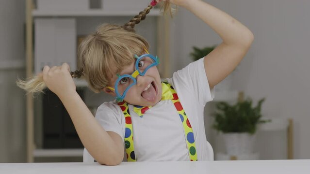 Funny girl of 7 years dressed in clown eye glasses, butterfly and suspenders.