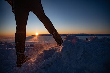 warmly dressed man wearing winter crampons on his boots during a winter ascent. Sunrise on Babia...