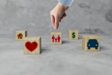 Wooden blocks with different icons and the hand that chooses the icon with the family. The concept...