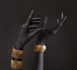 Black woman's hands with gold jewelry. Oriental Bracelets on a black painted hand. Gold Jewelry and luxury accessories on black background closeup.