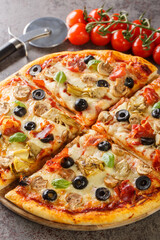 Freshly baked capricciosa pizza with artichokes, prosciutto ham, olives, mushrooms and cheese close-up on a wooden board on the table. Vertical